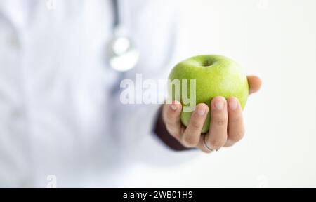 Abgeschnittene Frau mit medizinischem Mantel Arzt mit Apfel Stockfoto