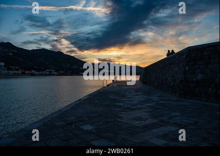 Cefalu, Sizilien, Italien, 19. Dezember 2023 - Sonnenuntergang von den Docks über dem Meer und den Bergen des Dorfes Stockfoto