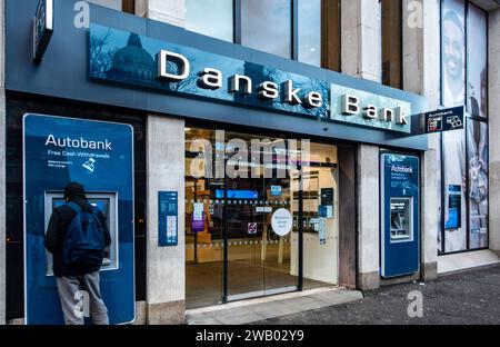 Ein Mann, der neben einem Geldautomaten der Danske Bank in Belfast, Nordirland, steht. Stockfoto