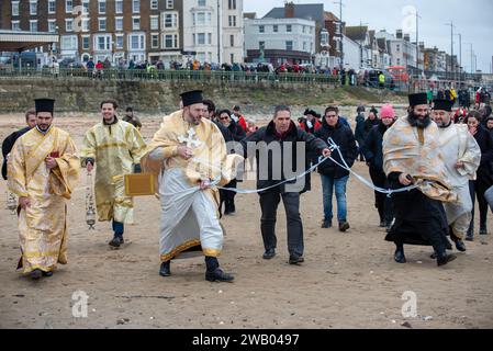 Margate, Großbritannien. Januar 2024. Priester laufen am Strand entlang zum Segensort. Die zyprische Diaspora organisierte Seegung, ein jährliches griechisch-orthodoxes religiöses Ereignis der Erleuchtung. (Foto: Krisztian Elek/SOPA Images/SIPA USA) Credit: SIPA USA/Alamy Live News Stockfoto