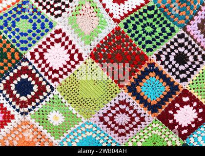 Schönes mehrfarbiges Karo, gestrickt aus Quadraten. Granny Quadrate sind aus rotem, gelbem, grünem, lila, blauem und orangem Garn gehäkelt Stockfoto