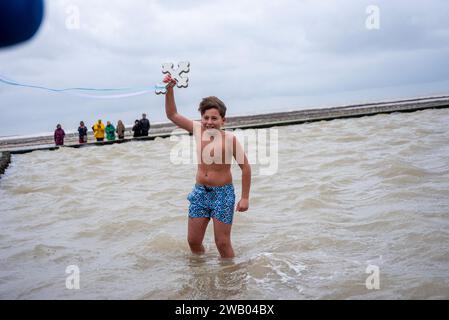 Margate, Großbritannien. Januar 2024. Raphael Florides (10) hält das Kreuz hoch, während er aus dem Wasser geht. Die zyprische Diaspora organisierte Seegung, ein jährliches griechisch-orthodoxes religiöses Ereignis der Erleuchtung. (Foto: Krisztian Elek/SOPA Images/SIPA USA) Credit: SIPA USA/Alamy Live News Stockfoto