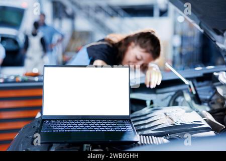 Modell-Laptop neben dem Servicebetrieb, der alte Autobremsflüssigkeit in der Werkstatt durch neue ersetzt. Isoliertes Bildschirmgerät und geschulter Werkstattarbeiter, der professionelle Ausrüstung für die Fahrzeugkontrolle verwendet Stockfoto