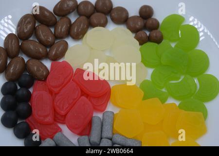 Eine Auswahl an ungewöhnlichen Marken-Gummibonbons in Form von grauen Metallzylindern, farbigen Elementen, Kapseln, Talismanen und Schokoladenstein Stockfoto