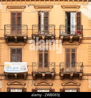 Palermo, Sizilien, Italien, 14. Dezember 2023 - orangefarbene Fassade mit Balkonen und Holzläden in einem traditionellen Wohnblock Stockfoto