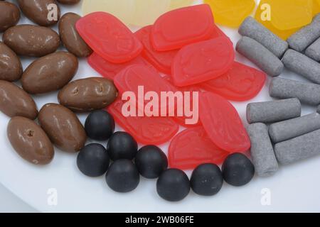 Eine Auswahl an ungewöhnlichen Marken-Gummibonbons in Form von grauen Metallzylindern, farbigen Elementen, Kapseln, Talismanen und Schokoladenstein Stockfoto