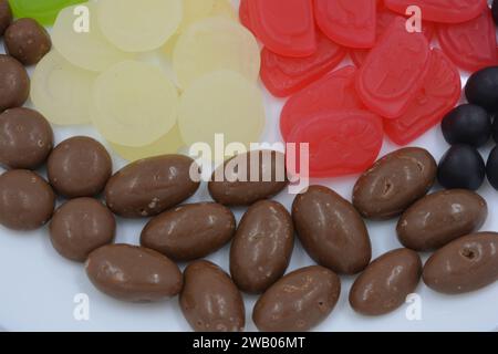 Eine Auswahl an ungewöhnlichen Marken-Gummibonbons in Form von grauen Metallzylindern, farbigen Elementen, Kapseln, Talismanen und Schokoladenstein Stockfoto