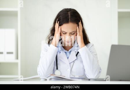 Gestresste junge Hausärztin in weißer Uniform Stockfoto