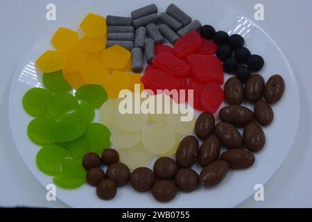 Eine Auswahl an ungewöhnlichen Marken-Gummibonbons in Form von grauen Metallzylindern, farbigen Elementen, Kapseln, Talismanen und Schokoladenstein Stockfoto