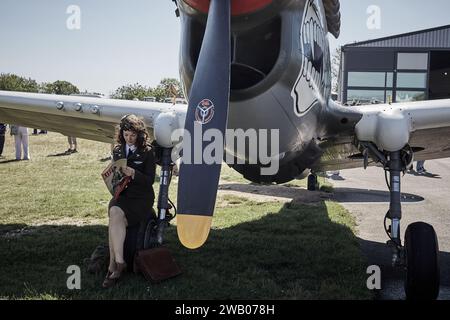 Militärangehörige, junge amerikanische Offizierin, die das Life-Magazin unter einem Flugzeug liest Stockfoto