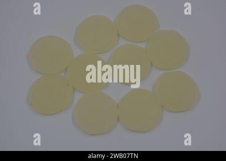 Helle, ungewöhnliche, gummiartige Bonbons in Form von blassgelben Talismanen auf weißem Hintergrund. Stockfoto