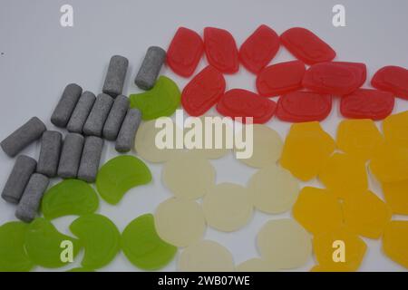 Eine Auswahl an ungewöhnlichen Marken-Gummibonbons in Form von grauen Metallzylindern, farbigen Elementen, Kapseln, Talismanen und Schokoladenstein Stockfoto