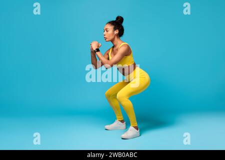 Fit Afroamerikanerin Macht Tiefe Squat-Übungen, Blauer Hintergrund Stockfoto