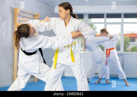 Paarungskurse in Judo oder Jiu Jitsu – zwei Teenager-Mädchen üben das Greifen und Werfen auf Sportmatten Stockfoto