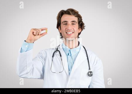 Glücklicher männlicher Arzt, der eine Nahrungspille zeigt Stockfoto
