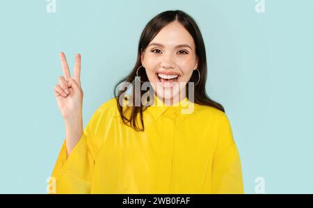 Emotional glückliche junge Frau, die Friedensgeste zeigt Stockfoto