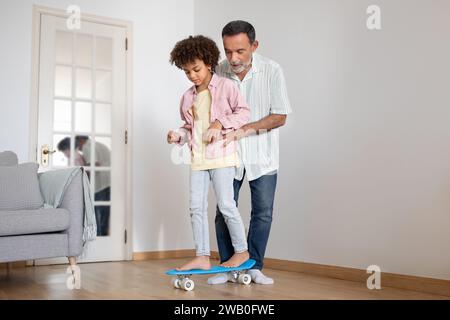 Reifer Opa Bringt Seinem Enkel Bei, Zu Hause Skateboard Zu Fahren Stockfoto