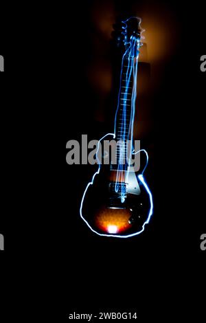 Eine Rock-and-Roll-Gitarre, die in hellen Streifen umrandet ist, mit langer, langsamer Verschlusszeit auf schwarzem Hintergrund. . Stockfoto