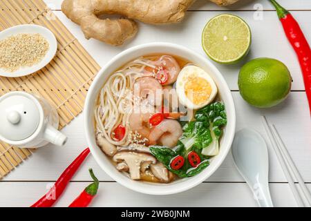 Leckere Ramen mit Garnelen in der Schüssel und Zutaten auf weißem Holztisch, flach gelegt Stockfoto