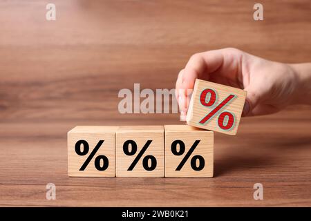 Bester Hypothekenzins. Frau, die einen Würfel mit rotem Prozent-Schild über Holztisch hält, Nahaufnahme Stockfoto