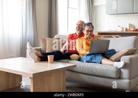Entspanntes, glückliches Seniorenpaar, das zu Hause ausgeruht und zusammen auf der Couch sitzt Stockfoto