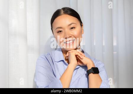 Porträt einer glücklichen Millennials-asiatin, die neben dem Fenster posiert Stockfoto