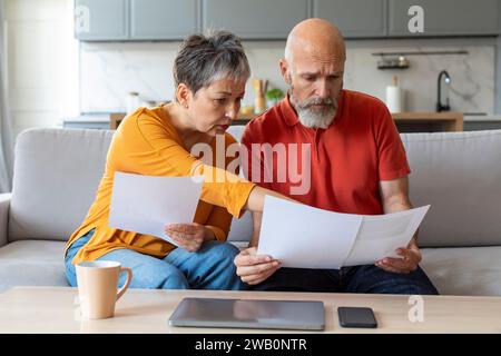 Budgetplanung. Besorgte Ältere Ehegatten Halten Papiere Und Berechnen Gemeinsam Familienausgaben Stockfoto