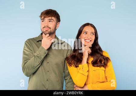 Nachdenkliches Paar mit neugierigen Ausdrücken, Hand am Kinn, aufschauen Stockfoto