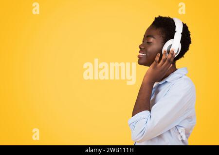 Eine fokussierte schwarze Studentin mit Kopfhörern, die in ihr Studium oder ihre Musik eingetaucht ist Stockfoto
