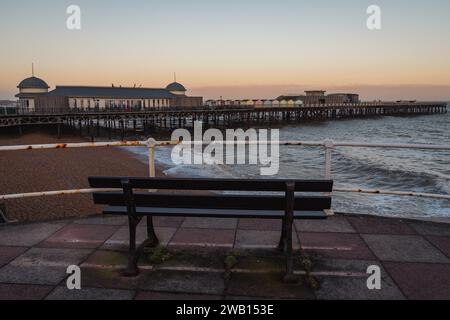 Hastings, East Sussex, England, Großbritannien - 11. Mai 2022: Abendliche Stimmung am Strand, mit einer Bank mit Blick auf den Pier Stockfoto