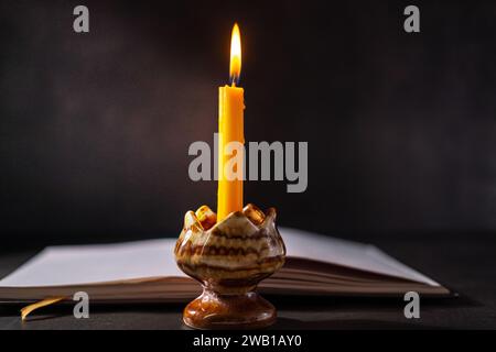 Gelber Kerzenhalter gibt beim Lesen Licht, schwarzer Hintergrund Stockfoto