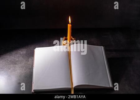 Gelber Kerzenhalter gibt beim Lesen Licht, schwarzer Hintergrund Stockfoto