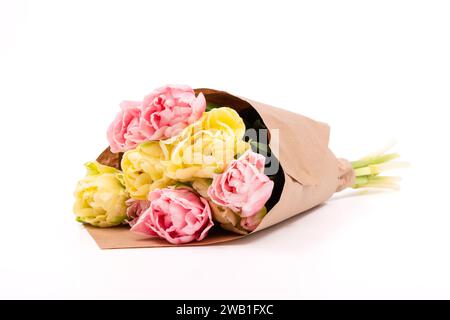 Ein Bündel von gelben und rosa doppelten Tulpen, die in recyceltem braunem Papier verpackt sind, isoliert auf weißem Hintergrund. Tulpenstrauß. Stockfoto