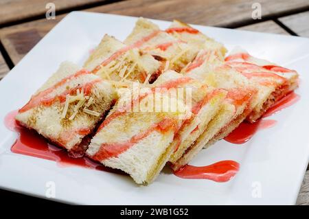 Toast mit Käse bestreut und mit Sirup mit Erdbeergeschmack bedeckt Stockfoto