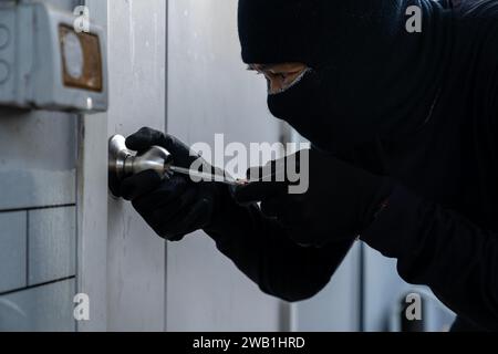 Ein Einbrecher zwingt eine Haustür auf Stockfoto