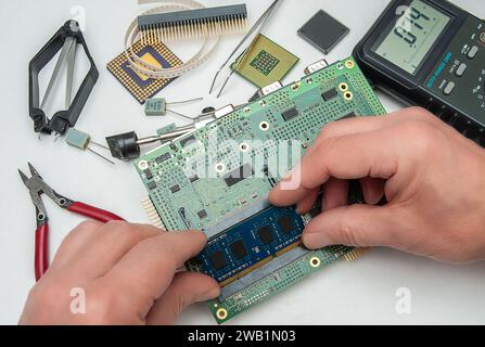 Nahaufnahme der Hände eines Technikers in einer Werkstatt. Der Techniker installiert ein SODIMM-Speichermodul auf einer industriellen integrierten CPU-Platine. Stockfoto