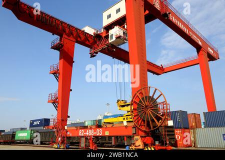 LIANYUNGANG, CHINA - 8. JANUAR 2024 - Großmaschinen beladen Container für den Güterzug China-Kasachstan (Lianyungang) auf der China-Kasachstan l Stockfoto