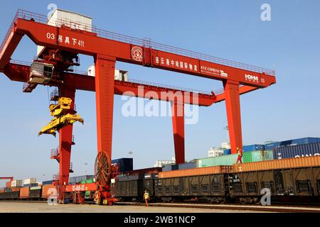 LIANYUNGANG, CHINA - 8. JANUAR 2024 - Großmaschinen beladen Container für den Güterzug China-Kasachstan (Lianyungang) auf der China-Kasachstan l Stockfoto