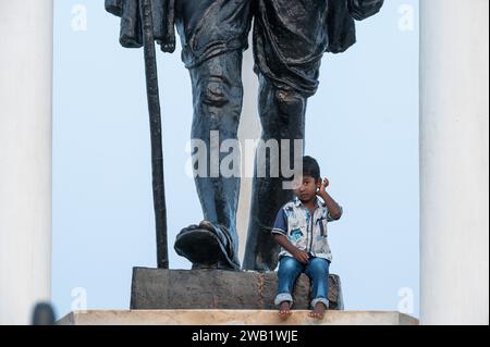 Kind am Fuße eines Mahatma Gandhi Monuments, Statue, ehemalige französische Kolonie Pondicherry oder Puducherry, Tamil Nadu, Indien Stockfoto