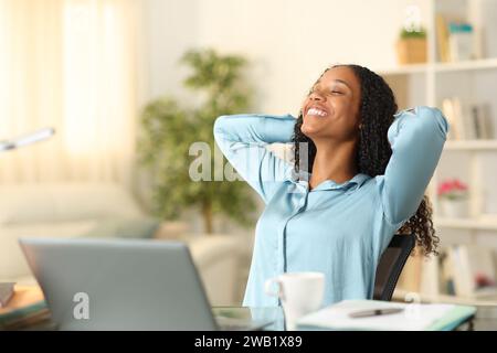 Glücklicher Telearbeiter, der sich entspannt und atmet, während er zu Hause arbeitet Stockfoto