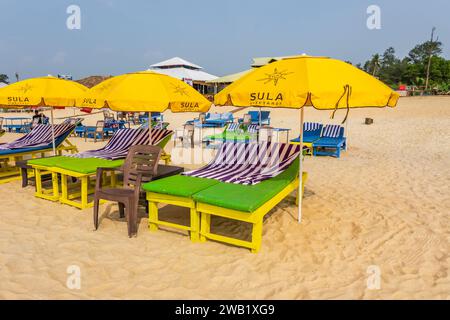 Bunte hölzerne Sonnenschirme und Liegestühle am Sandstrand des Meeres Stockfoto