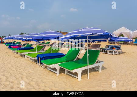 Bunte hölzerne Sonnenschirme und Liegestühle am Sandstrand des Meeres Stockfoto