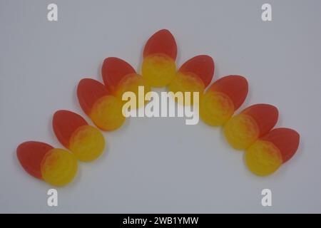 Gebrandete, werkseitig hergestellte gummiartige Kinderbonbons in Form von kleinen Früchten, Wolfsbeeren und gelben Beeren auf weißem Hintergrund. Stockfoto