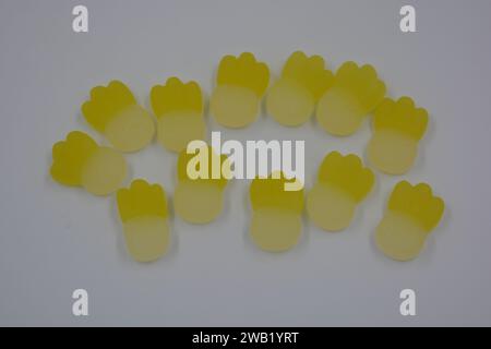 Gebrandete, werkseitig gefertigte gummiartige Kinderbonbons in Form von kleinen Früchten, Ananas auf weißem Kunststoffhintergrund. Stockfoto