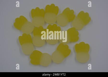 Gebrandete, werkseitig gefertigte gummiartige Kinderbonbons in Form von kleinen Früchten, Ananas auf weißem Kunststoffhintergrund. Stockfoto