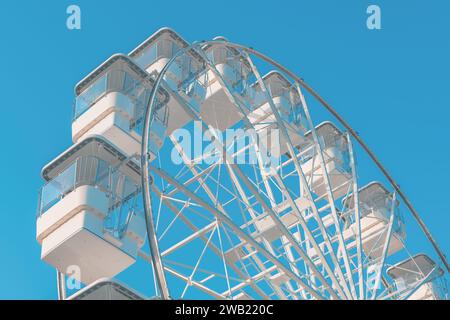 Das riesige weiße Riesenrad für Panoramablick im Vergnügungspark ist eine beliebte unterhaltsame Fahrt, die am hellen, sonnigen Tag am blauen Himmel geschossen wird Stockfoto