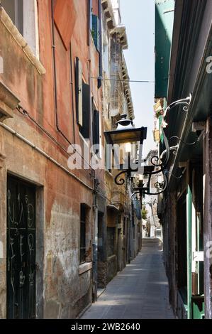 Enge Gasse im Zentrum der italienischen Stadt Padua mit alten verwitterten Häusern auf beiden Seiten mit einer alten dekorativen Außenlaterne darüber Stockfoto