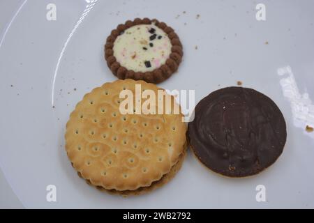 Auf einer weißen Glasplatte sind gebrandete, werkseitig hergestellte Kekse verschiedener Art angeordnet. Stockfoto