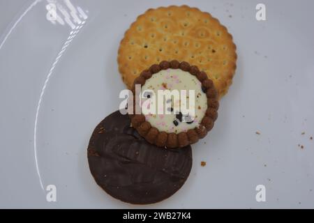 Auf einer weißen Glasplatte sind gebrandete, werkseitig hergestellte Kekse verschiedener Art angeordnet. Stockfoto