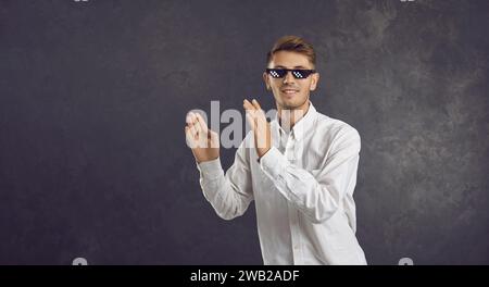 Glücklicher junger Mann in der Lebensbrille des Schlägers, der isoliert auf einem Kopierraum-Hintergrund tanzt Stockfoto